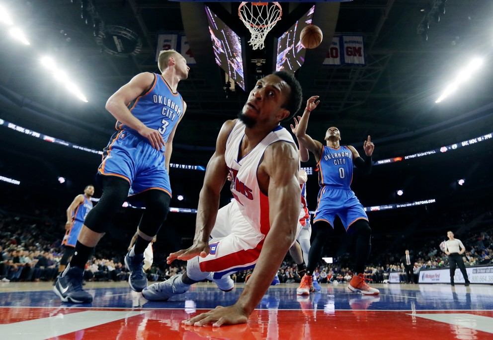 Ish Smith z Detroitu (v strede) padá na zem po zakončení v zápase proti Oklahoma City.