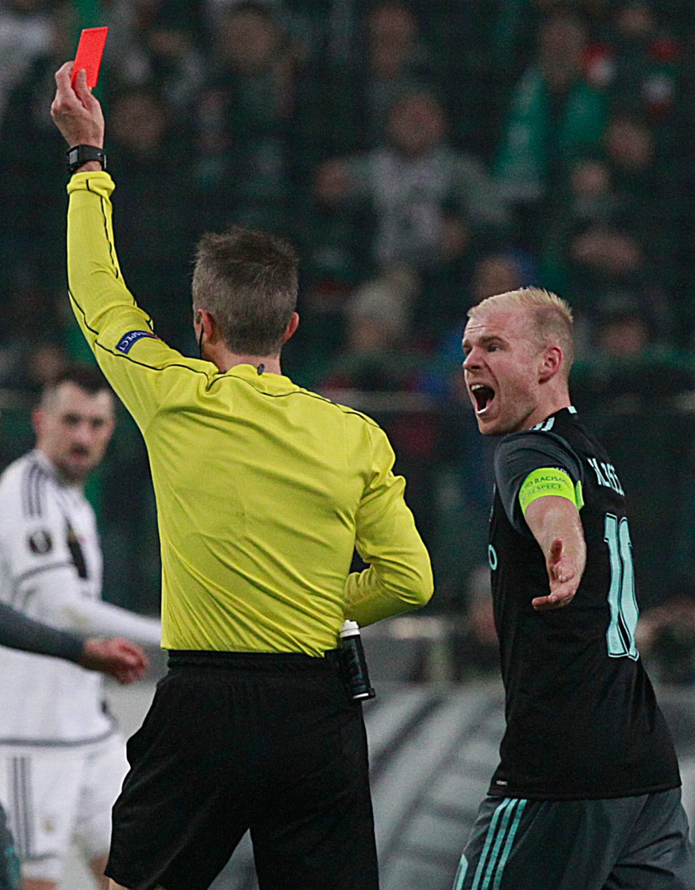 Kapitán Ajaxu Amsterdam Davy Klaassen (vpravo) sa háda s rozhodcom po tom, ako ukázal červenú kartu jeho spoluhráčovi Kennymu Tetemu.