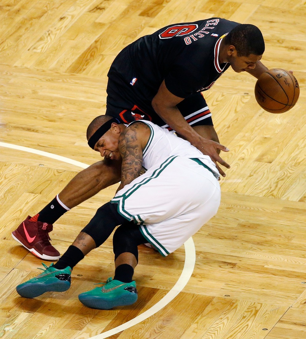 Isaiah Thomas z Bostonu (v bielom) padá v súboji s Cristianom Feliciom z Chicaga Bulls.