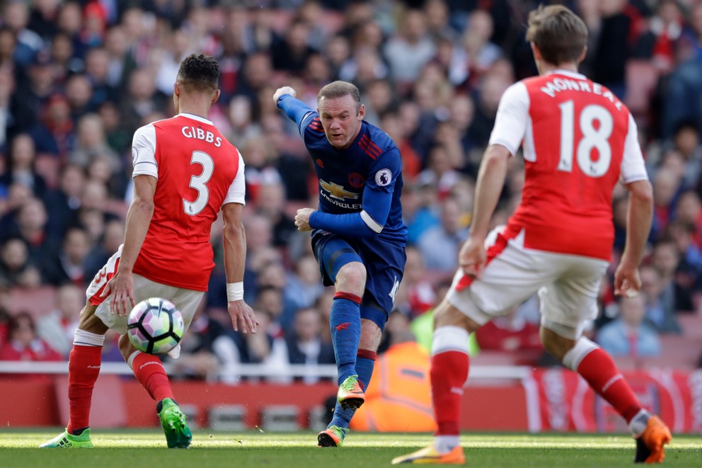 Wayne Rooney (v strede) strieľa loptu na bránu Arsenalu.
