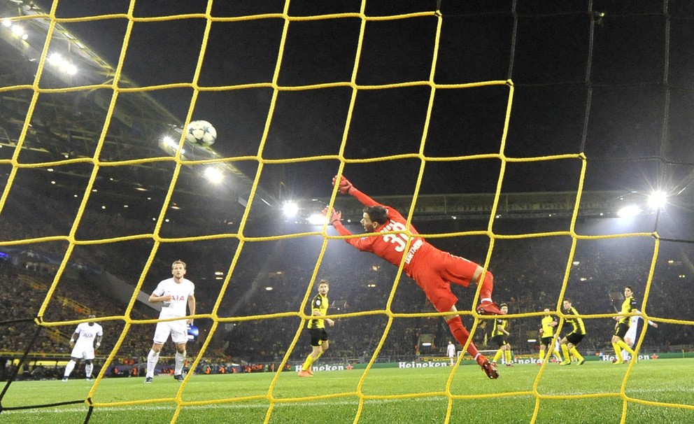 Brankár Dortmundu Roman Bürki sa márne naťahuje za loptou po strele Son Heung-mina.