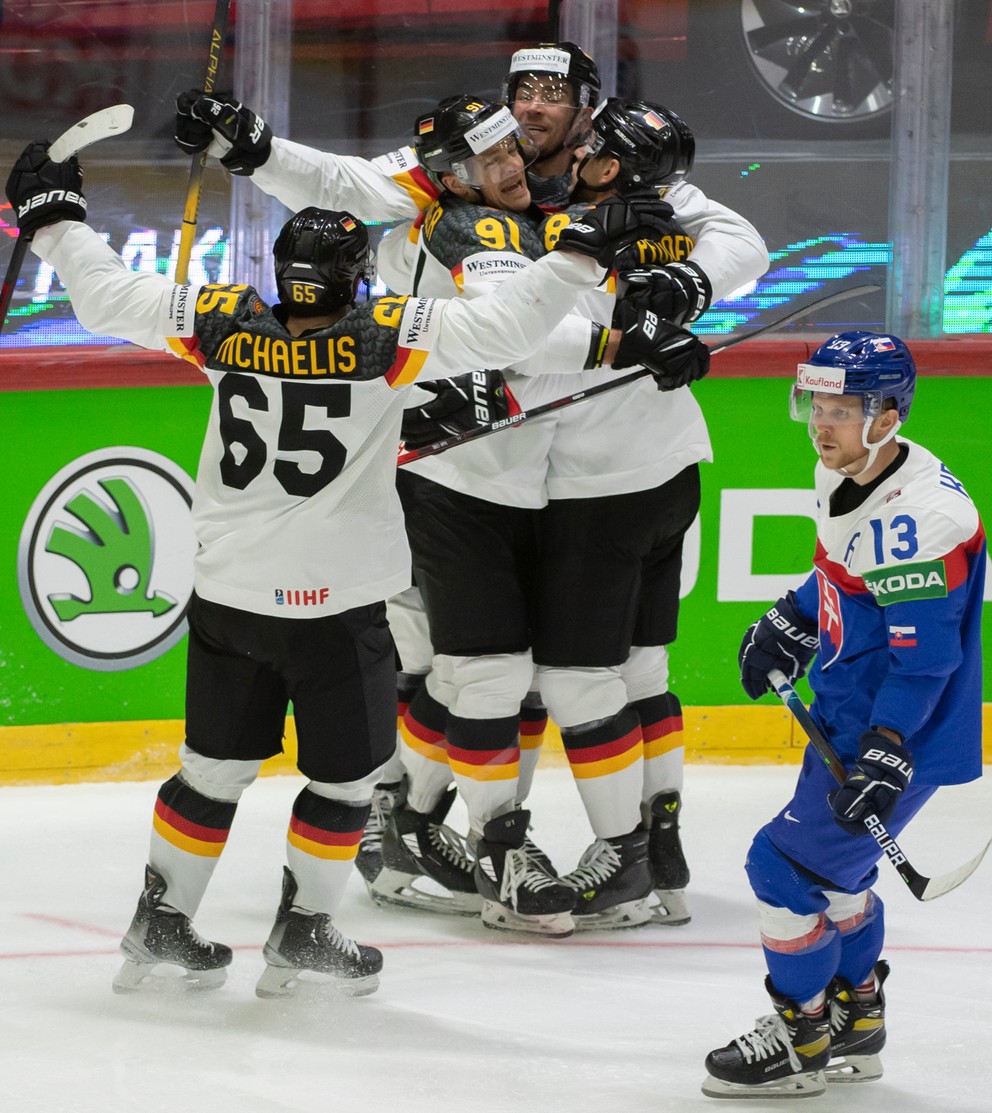 Nemeckí hokejisti sa tešia po strelení gólu, vpravo korčuluje slovenský hokejista Michal Krištof.