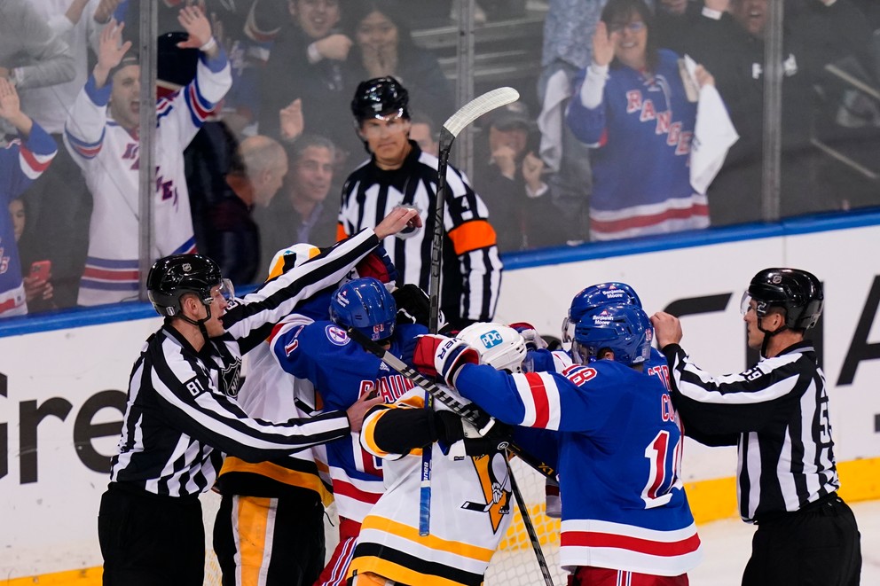 Rozhodcovia rozdeľujú šarvátku medzi hráčmi Pittsburghu a New Yorku Rangers.