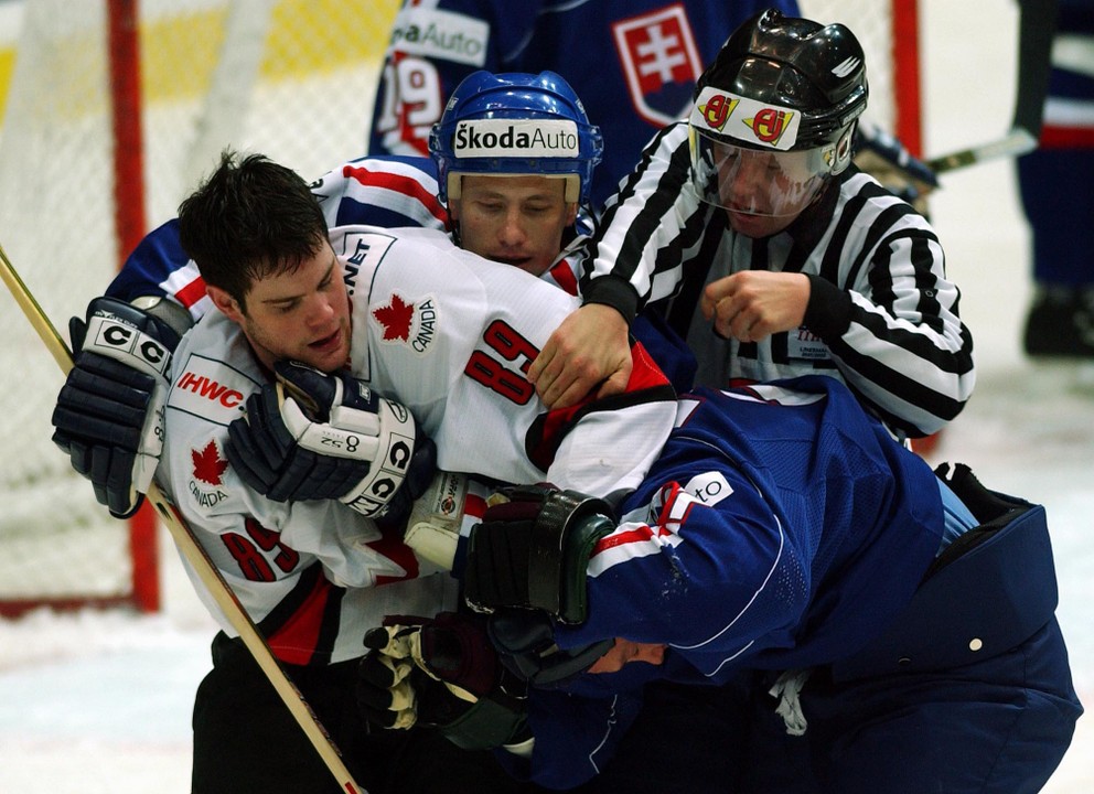 Kanaďan Mike Comrie drží Ladislava Nagya vo štvrťfinále MS v hokeji 2002. V pozadí Dušan Milo.