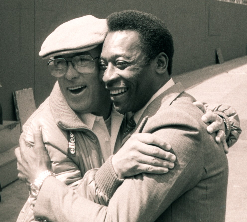 Brazílska futbalová hviezda Pelé a tréner New York Cosmos Julio Mazzei sa objímajú na Giants Stadium v East Rutherford, N.J., 16. apríla 1982. Mazzei pomohol presvedčiť Pelého, aby hral v Spojených štátoch a trénoval Cosmos k titulu Severoamerickej futbalovej ligy v roku 1982.