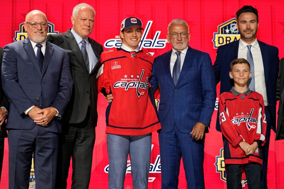 Osmička draftu NHL 2023 Ryan Leonard pózuje pri fotke s predstaviteľmi klubu Washington Capitals.