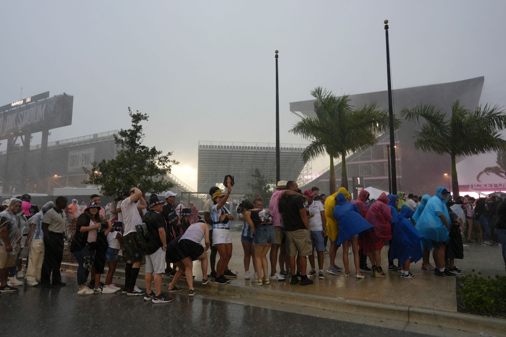 Fanúšikovia čakajú v daždi, kým ich pustia na štadión v Miami.