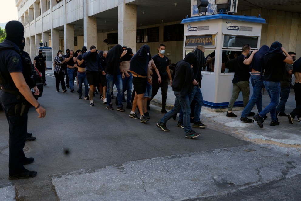 Policajti eskortujú z policajnej stanice futbalových fanúšikov, z ktorých väčšina  pochádza z Chorvátska v gréckej metropole Atény.