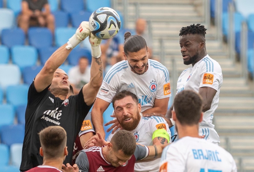 Brankár Podbrezovej Richard Ludha vyráža loptu pred hráčmi bratislavského Slovana.