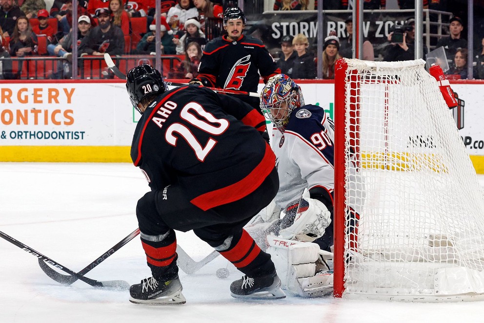 Fínsky útočník Sebastian Aho pred brankárom Elvisom Merzlikinšom.