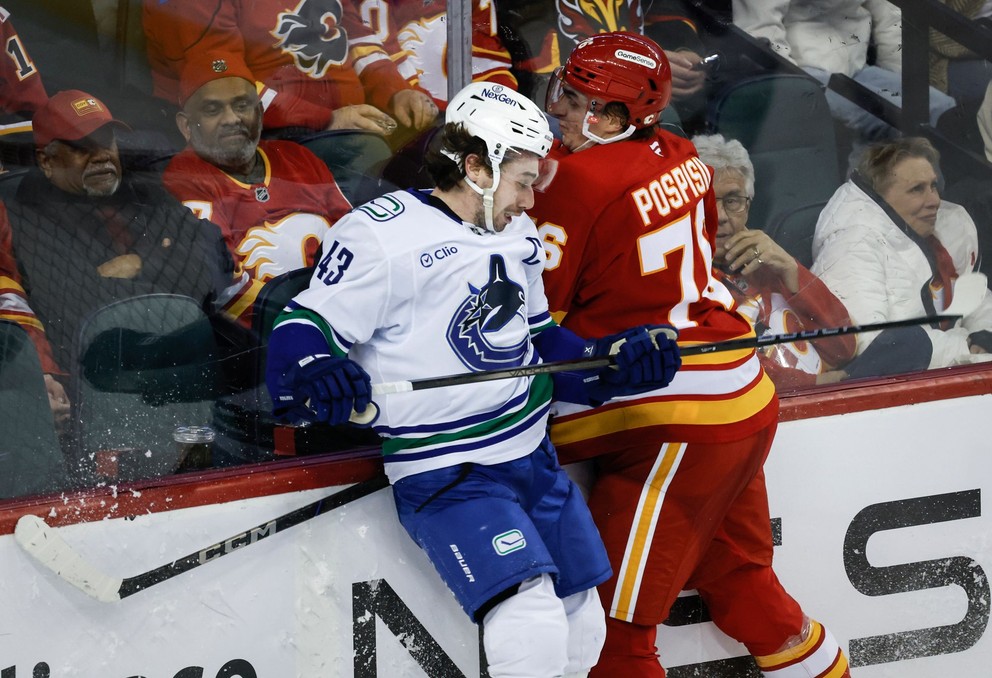 Slovenský útočník Martin Pospíšil (Calgary) v súboji pri mantineli s Quinnom Hughesom (Vancouver). 