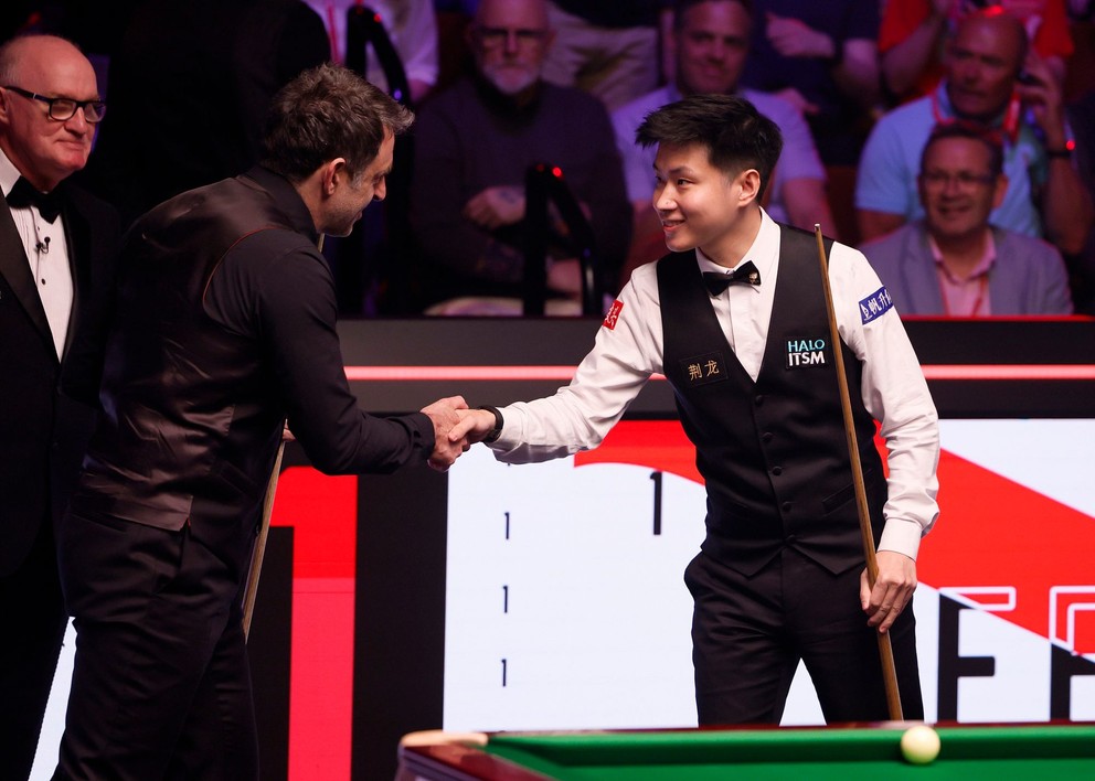 Ronnie O'Sullivan (vľavo) a Čao Sin-tchung (Xintong Zhao) počas semifinále MS v snookri 2025.
