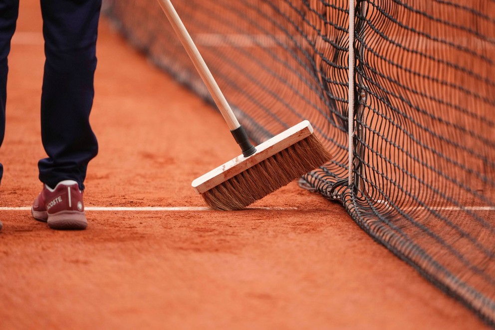 Pracovník zametá antuku počas Roland Garros 2025.