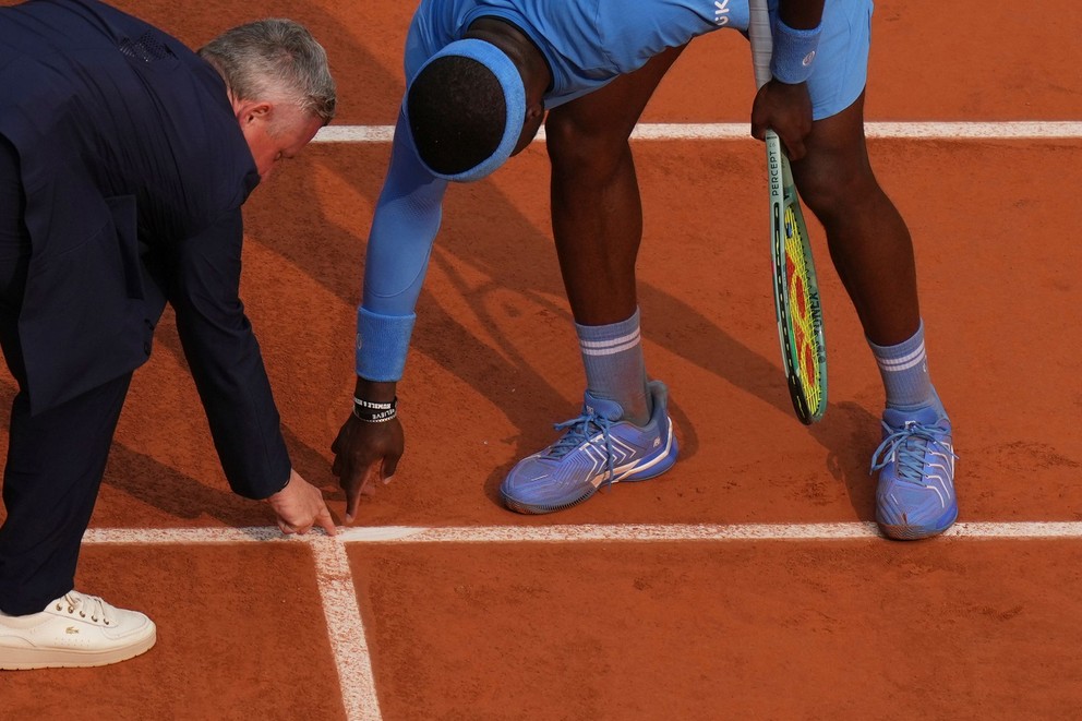 Frances Tiafoe ukazuje rozhodcovi dopad loptičky na antuke počas Roland Garros 2025.
