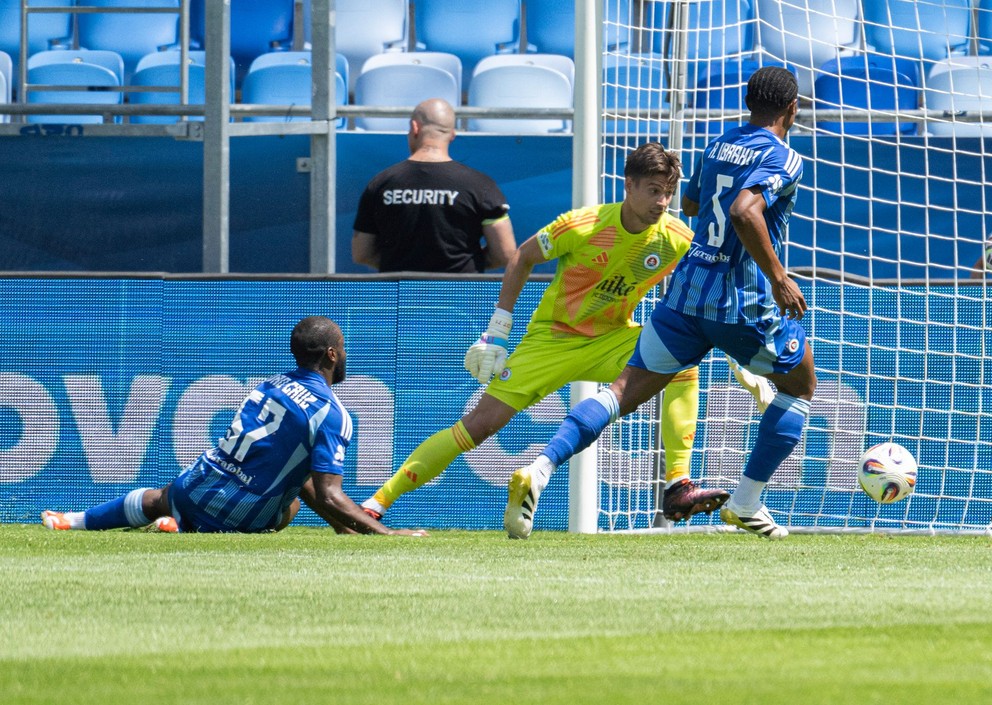 Na snímke zľava hráč Slovana Sandro Cruz si dáva vlastný gól, pozerajú sa spoluhráči brankár Dominik Takáč a Rahim Ibrahim počas prípravného zápasu medzi ŠK Slovan Bratislava - FC Midtjylland 13. júla 2025 v Bratislave.