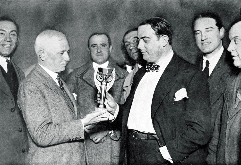 Prezident FIFA Jules Rimet (vľavo) a šéf Uruguajského futbalového zväzu Raúl Jude s trofejou Victory pre majstrov sveta vo futbale. Neskôr dostala meno po Rimetovi. V roku 1966 v Londýne ju ukradli, no o týždeň našli aj vďaka psovi Picklesovi v kríkoch. Definitívne zmizla v roku 1983 v Brazílii, ktorá ju mala ako trojnásobný šampión vo vlastníctve.