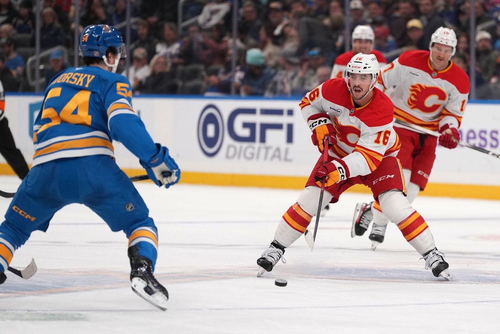 Morgan Frost z tímu Calgary Flames (16) sa snaží prihrávať, zatiaľ čo Dalibor Dvorský zo St. Louis Blues (54) bráni.