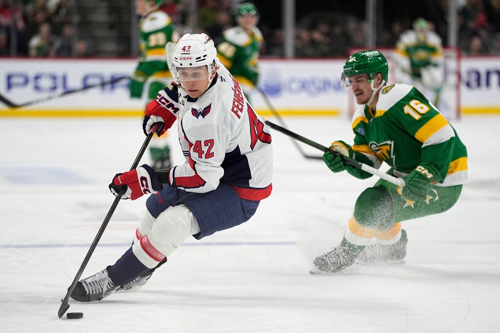 Obranca Washingtonu Capitals Martin Fehérváry (42) korčuľuje s pukom, zatiaľ čo ho sleduje pravé krídlo Minnesoty Wild Nicolas Aube-Kubel (16).