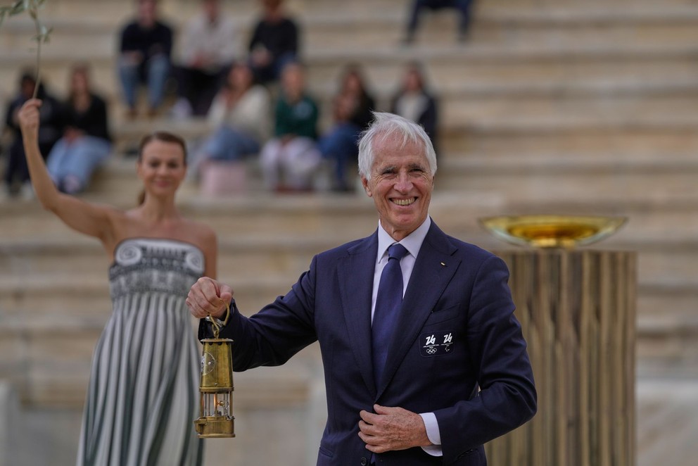 Prezident organizačného výboru Giovanni Malagò drží lampáš s olympijským ohňom počas ceremoniálu odovzdania pochodne pre ZOH 2026.