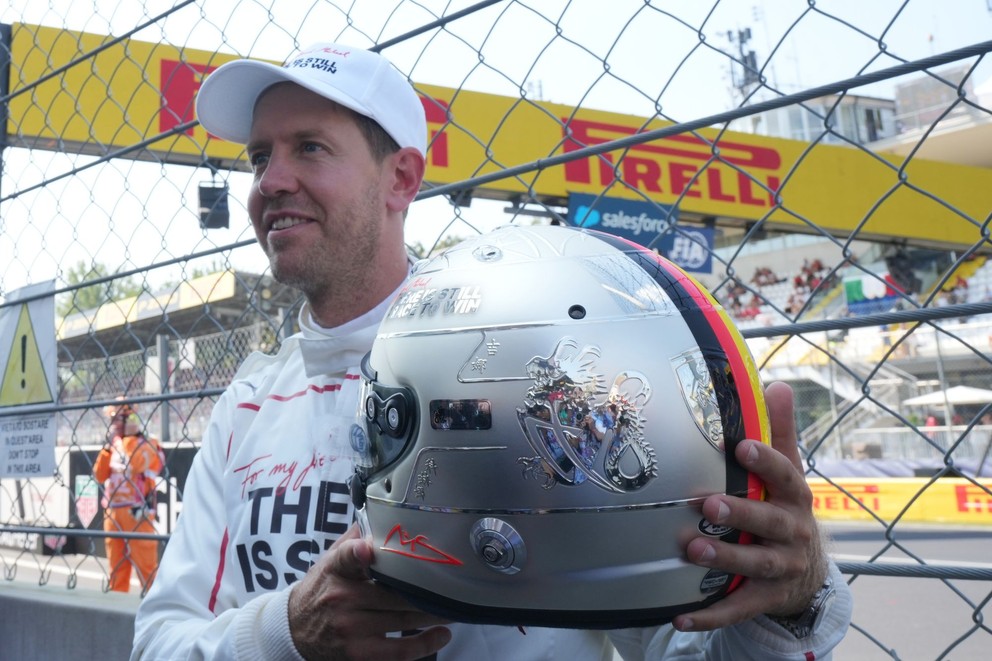 Bývalý jazdec Ferrari Sebastian Vettel drží helmu pri príležitosti 30. výročia debutovej sezóny Michaela Schumachera v radoch Ferrari pred Veľkou cenou Talianska na okruhu v Monze.