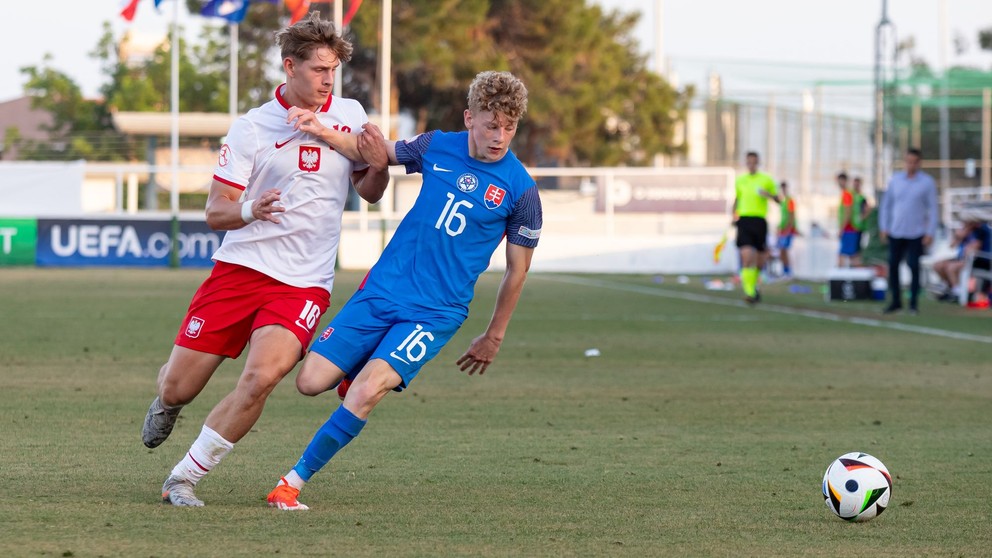 V nominácii je aj 11 futbalistov, ktorí sa v máji predstavili na ME do 17 rokov na Cypre. Medzi nimi aj Samuel Kováčik (na snímke v modrom v súboji s Baroszom Krieglerom v zápase proti Poľsku 17 na ME do 17 rokov, 27.5.2024)